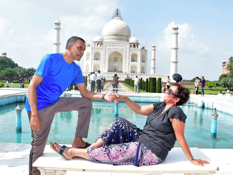 Two people sitting by a pool with the Taj Mahal in the background. 5