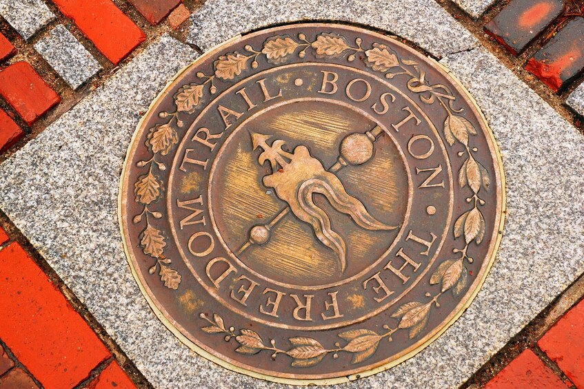 Una targa metallica con l'incisione 'TRAIL BOSTON THE FRESH BOSTON', circondata da motivi decorativi a foglia. 5