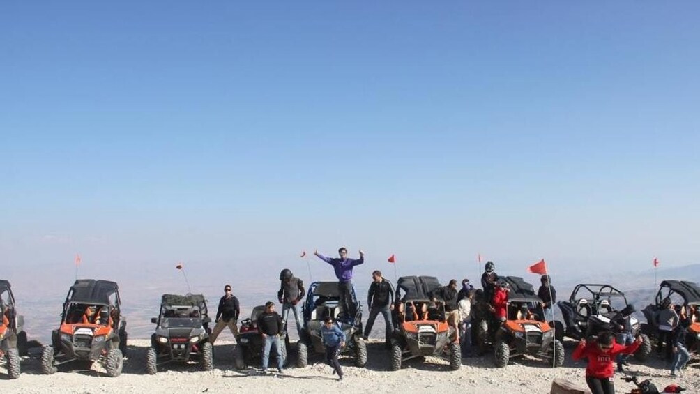 A group of people on ATVs at a high-altitude location with flags. 4