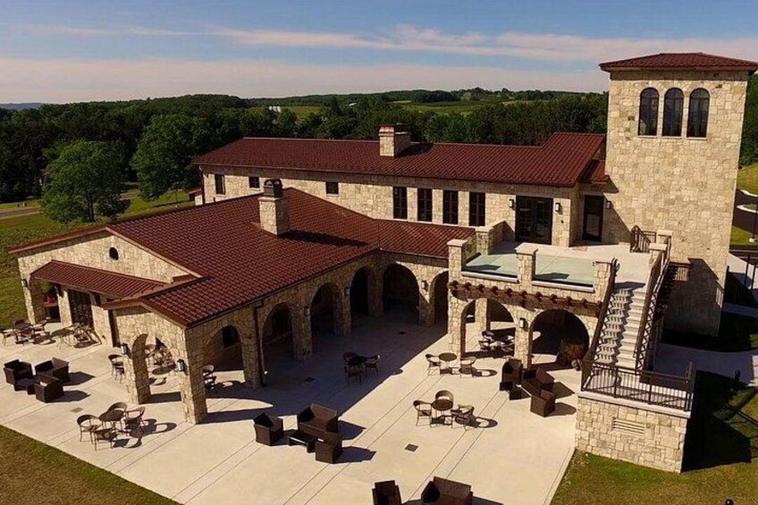 A large stone building with a red roof, multiple arches, and outdoor seating areas. 2