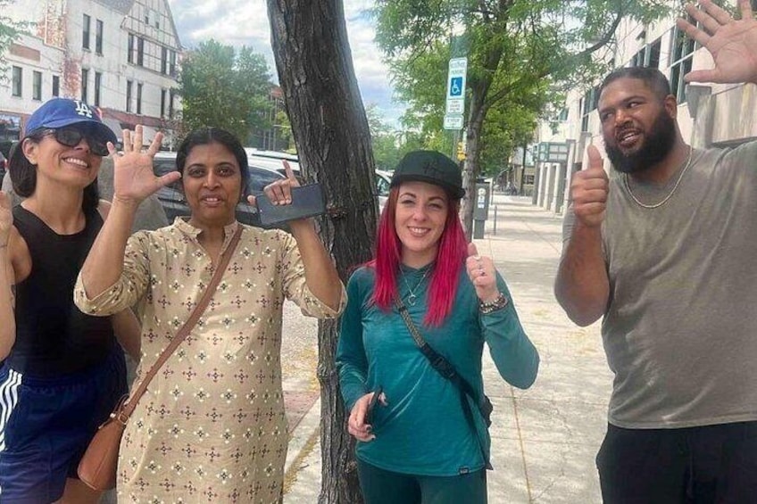 Un grupo de personas de pie en una acera, con árboles y edificios al fondo. 2