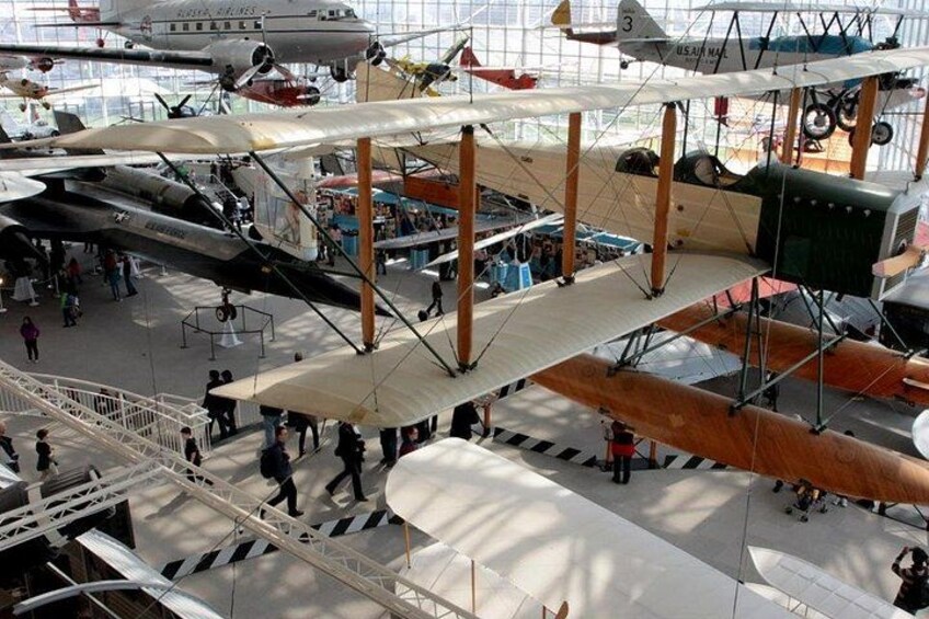 A museum with various aircraft on display, including biplanes and a single-engine plane. 5