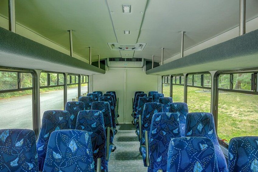A bus interior with rows of blue patterned seats, a central aisle, and windows on both sides. 4