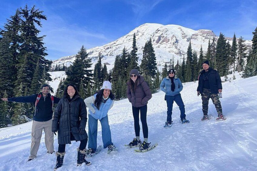 Un grupo de personas en una montaña nevada, con árboles y cielo despejado. 2
