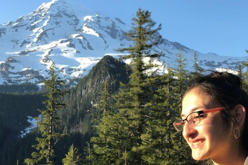 Une montagne aux sommets enneigés, une forêt verdoyante et dense, et une personne portant des lunettes. 2