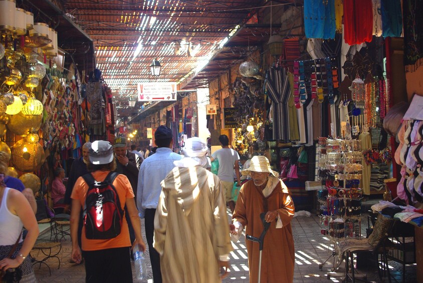 A bustling market with various stalls selling textiles, jewelry, and other goods. 2