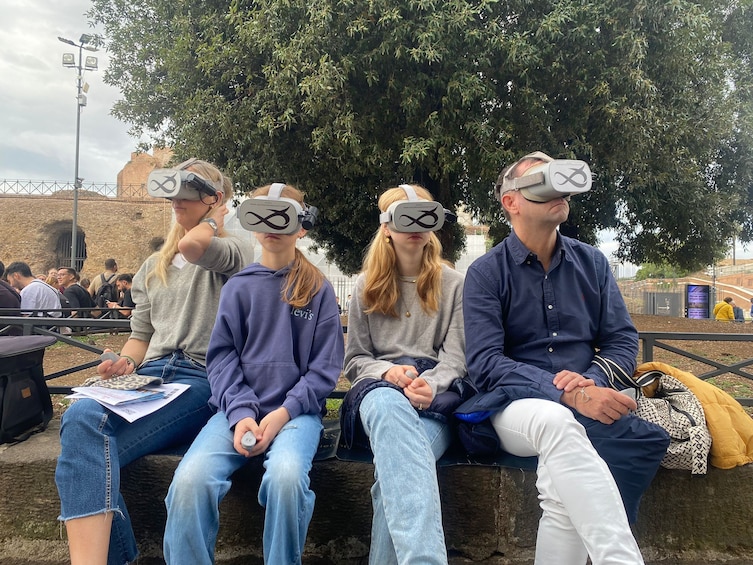 Four people wearing VR headsets sitting on a stone bench outdoors. 5