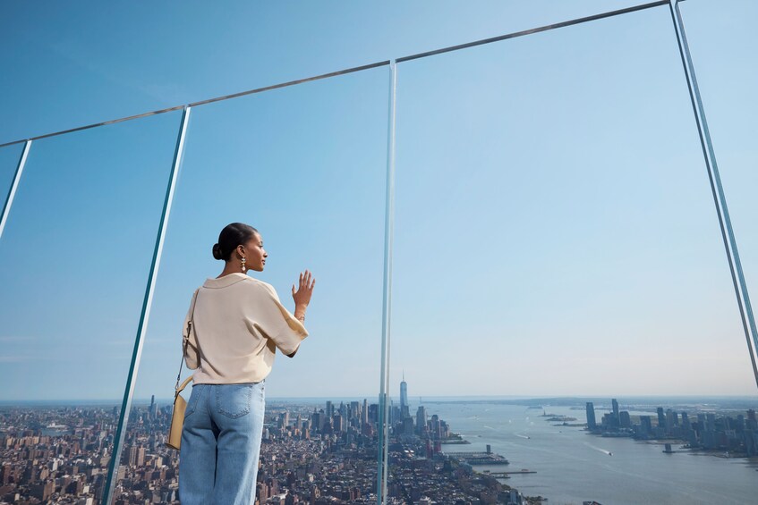 A person standing on a high-rise overlooking a cityscape with a river and bridges. 3