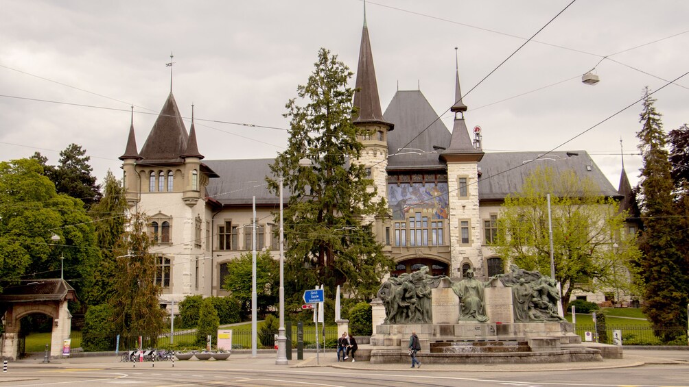 A historic building with multiple spires and a statue in front. 5