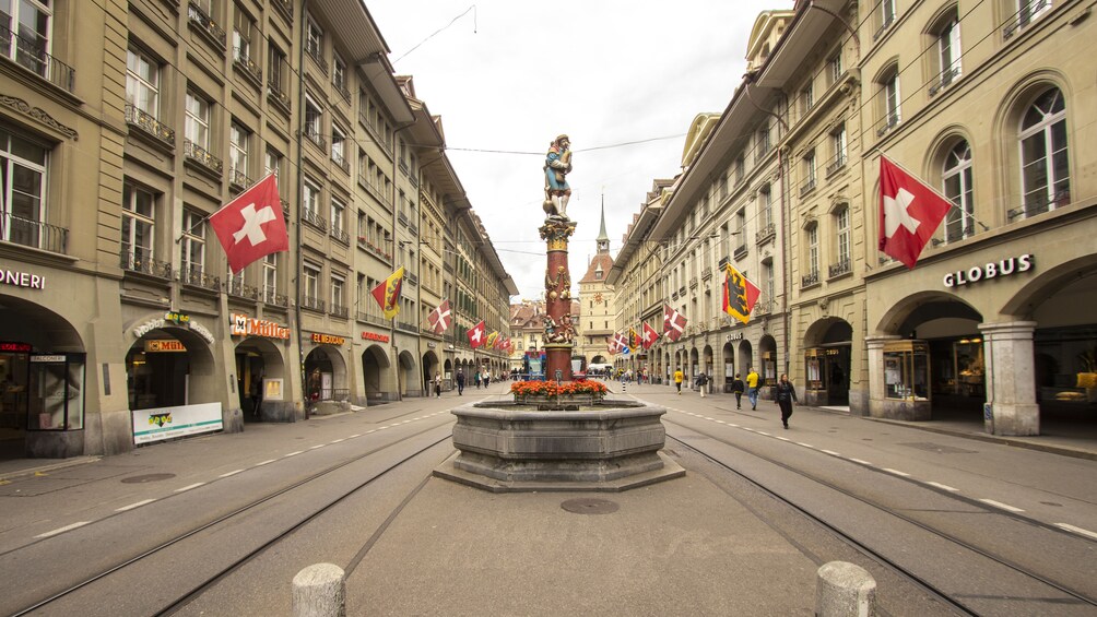 A street with shops and a central fountain. 1