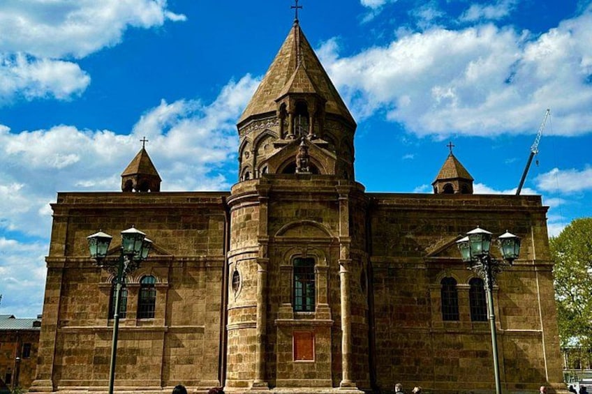 A historic church with a central tower, two smaller towers, and a cross on top. 1