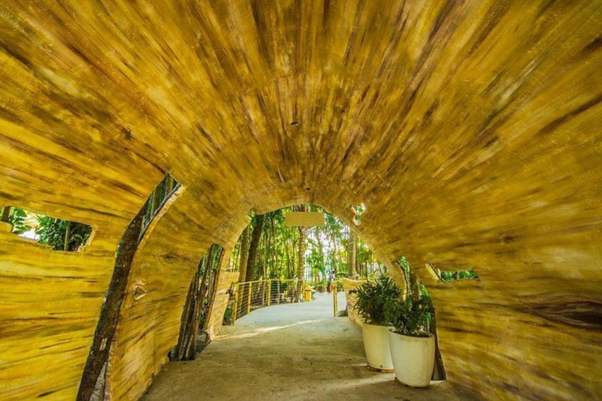 A tunnel with wooden walls and a concrete floor, leading to a covered area with plants. 4