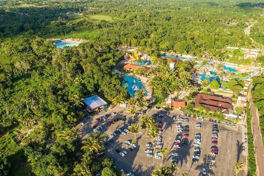 A resort with multiple swimming pools, a parking lot, and lush greenery. 3