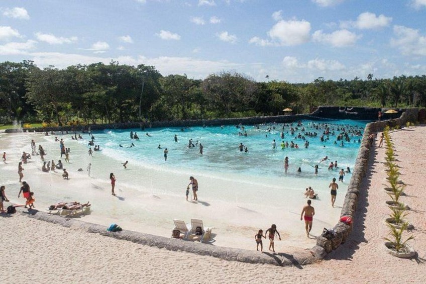 A crowded beach with a large pool and people swimming. 5