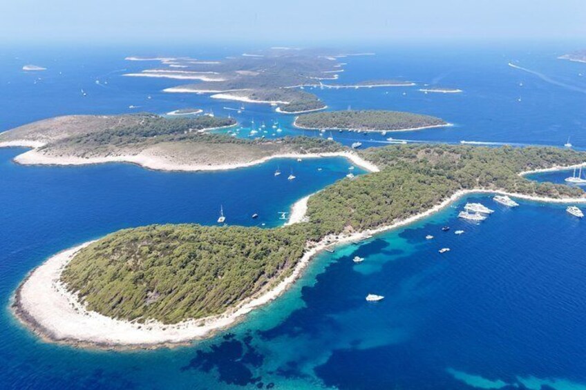 An aerial view of a coastal archipelago with clear blue waters, green islands, and boats. 5