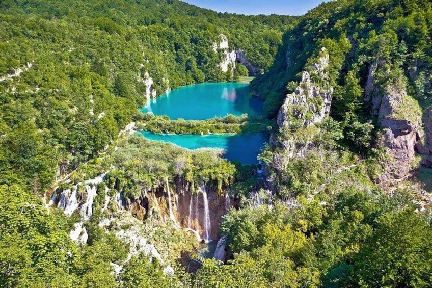 A turquoise lake surrounded by forested cliffs. 1