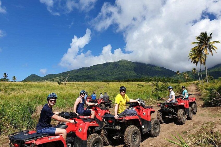 A group of people on ATVs in a grassy field with mountains in the background. 4
