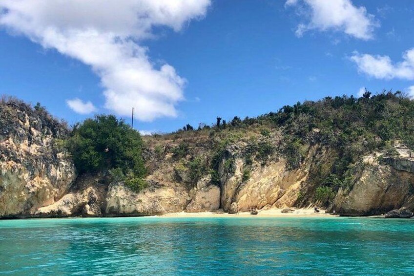 Paisaje costero con aguas turquesas cristalinas, playa arenosa y acantilados rocosos. 2