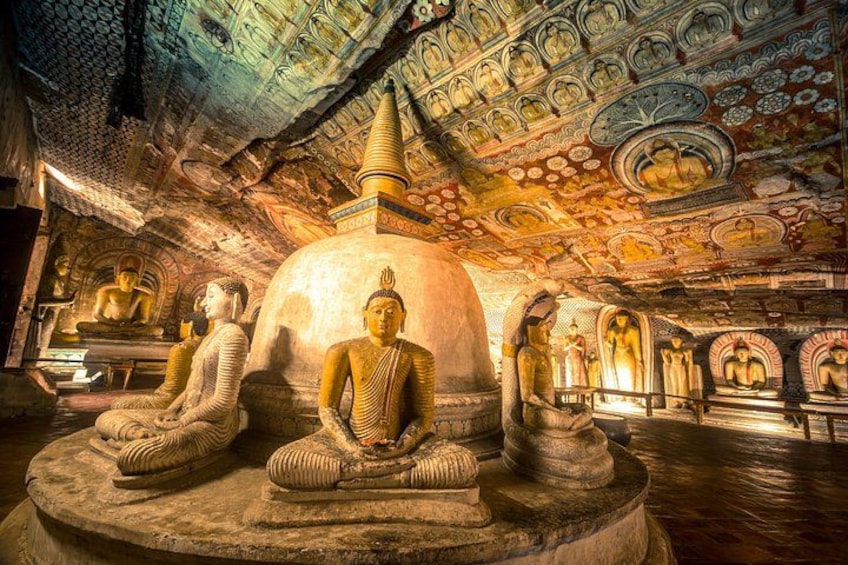 Et tempelinteriør med store Buddha-statuer, detaljeret loftkunst og stensnitterier. 4