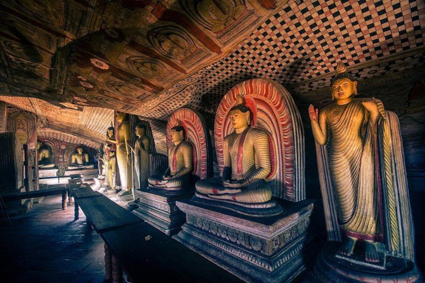 Et tempelinteriør med flere Buddha-statuer og detaljerede carvings i loftet. 5