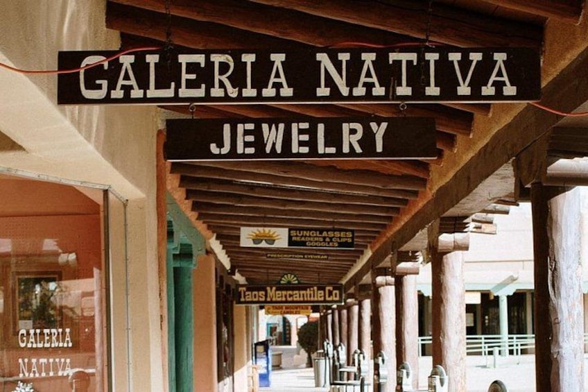 En butik med en skylt som visar texten ”GALERIA NATIVE JEWELRY” och en annan skylt för ”TAS MERCANTILE CO.”. 3