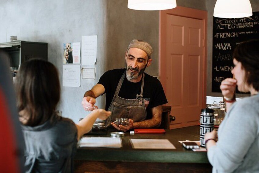 A barista serving coffee to customers at a counter with a menu board in the background. 1