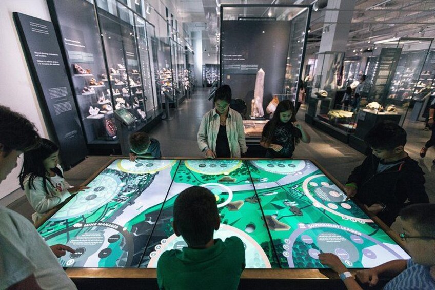 A group of people interacting with a large interactive display in a museum. 3