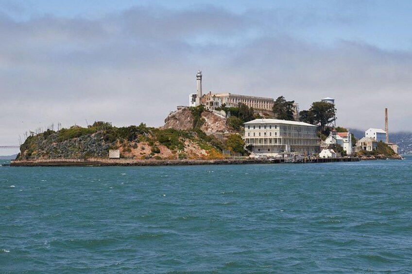 A lighthouse on a rocky island with a building and a bridge in the background. 5