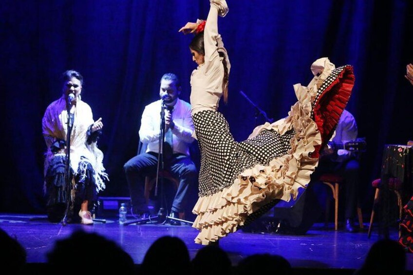 A person performing a dance on stage with a microphone stand and another person in the background. 4