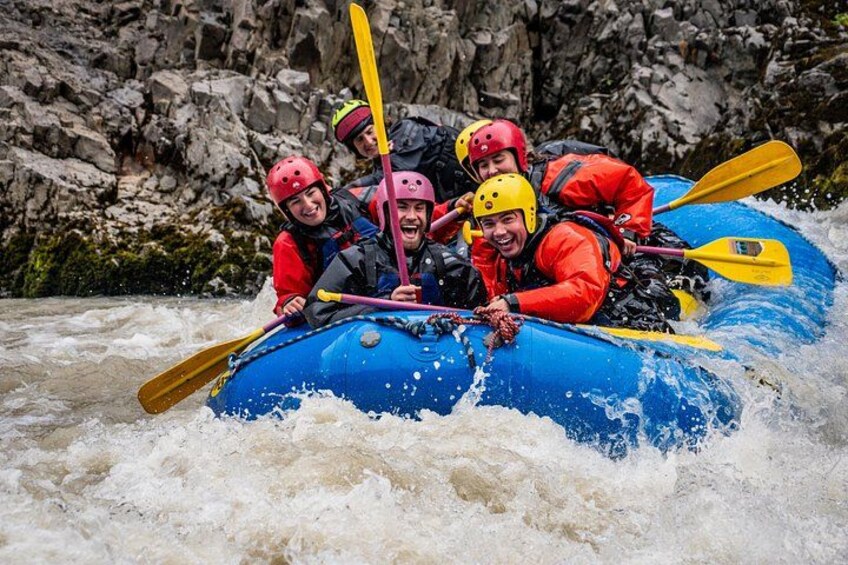 A group of people in a blue raft navigating a river with rapids. 4