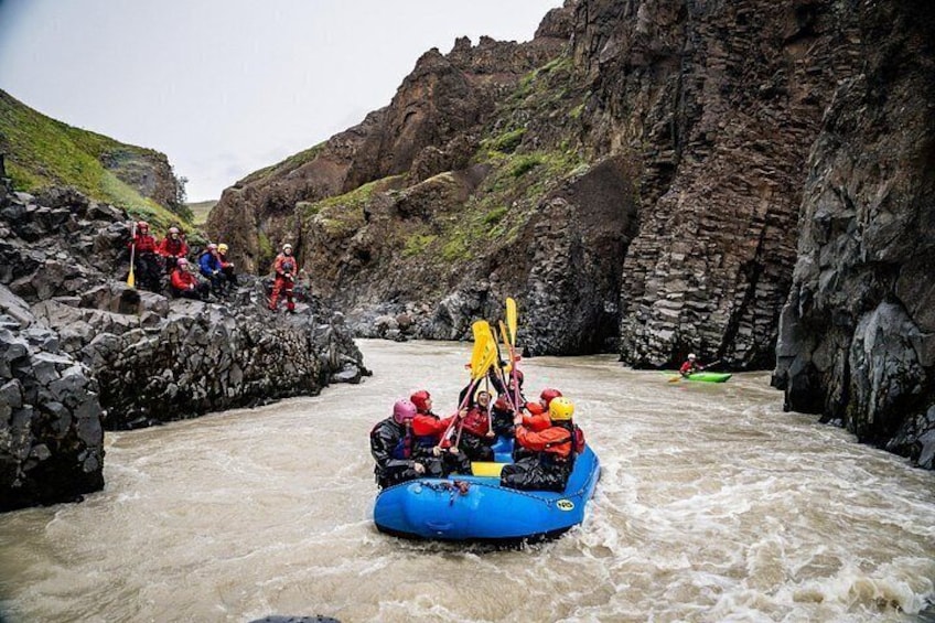 A group of people rafting in a rocky canyon with a blue raft. 2