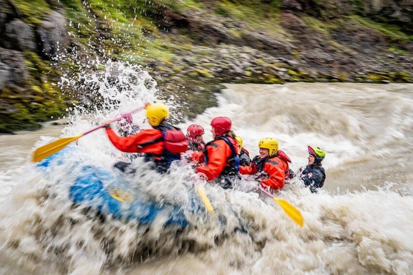 A group of people in a blue raft navigating a turbulent river. 5