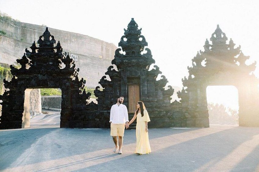 A man and a woman walking in front of ancient stone structures with intricate carvings. 3