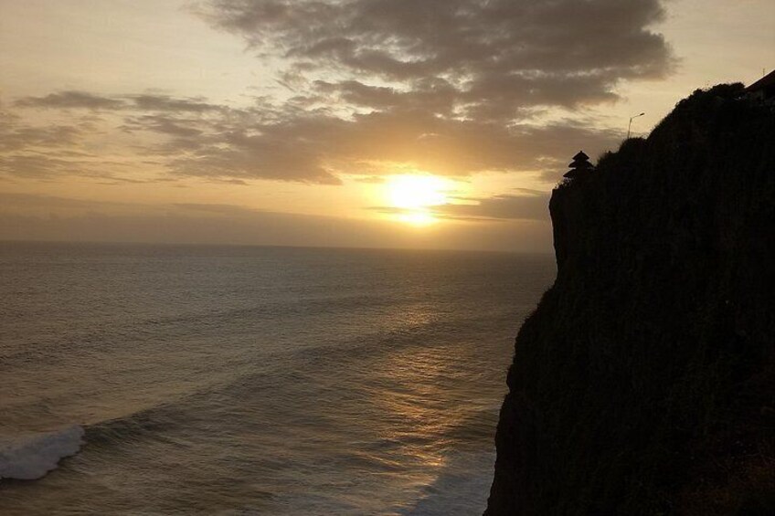 A sunset over the ocean with a cliff in the foreground. 5