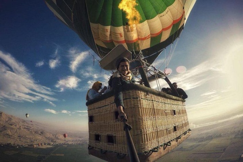 Una mongolfiera con passeggeri e un cestello che sorvola un paesaggio. 1