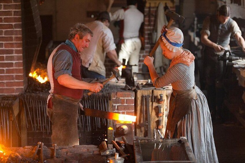 Two individuals working with a forge, surrounded by fire and tools. 2