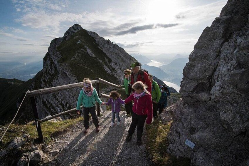 Een groep wandelaars op een bergpad met rotsachtig terrein en uitzicht op verre bergen. 3