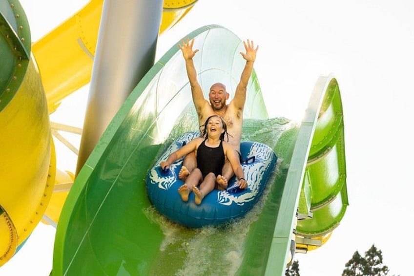 A water slide with a person and a child on a blue tube. 4