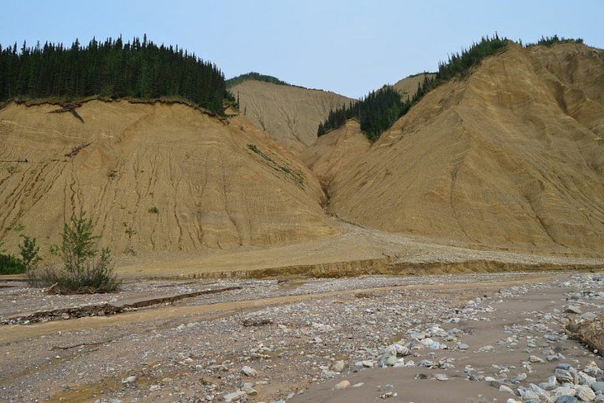 A rocky terrain with a riverbed and forested hills. 2