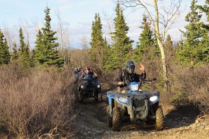 Two off-road vehicles on a dirt trail surrounded by trees. 1