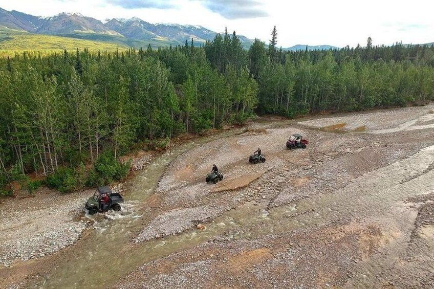 A river crossing with four off-road vehicles navigating the terrain. 3