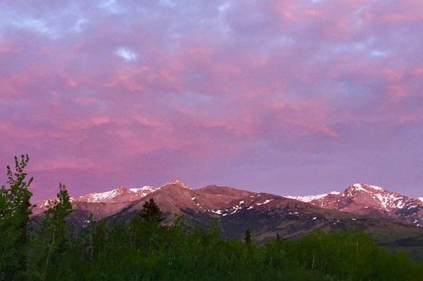 A mountain range with snow-capped peaks under a pink sky. 4