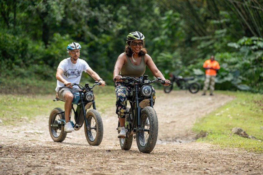 Deux personnes font du vélo tout terrain sur un sentier de terre, entourées de verdure. 2