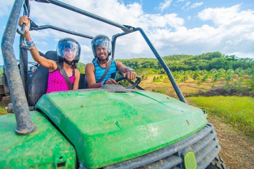 Dos personas en un vehículo verde con un paisaje rural de fondo. 1