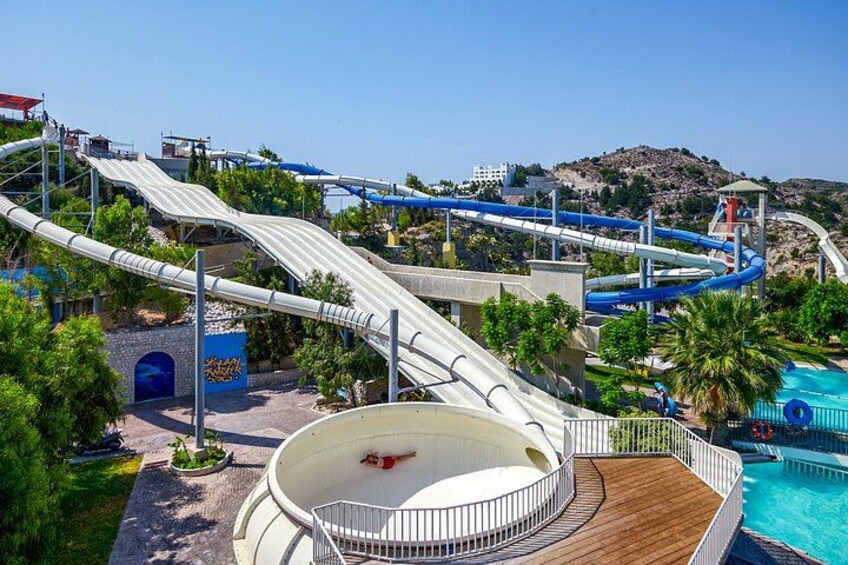 A water park with a large pool, a water slide, and a mountain in the background. 3