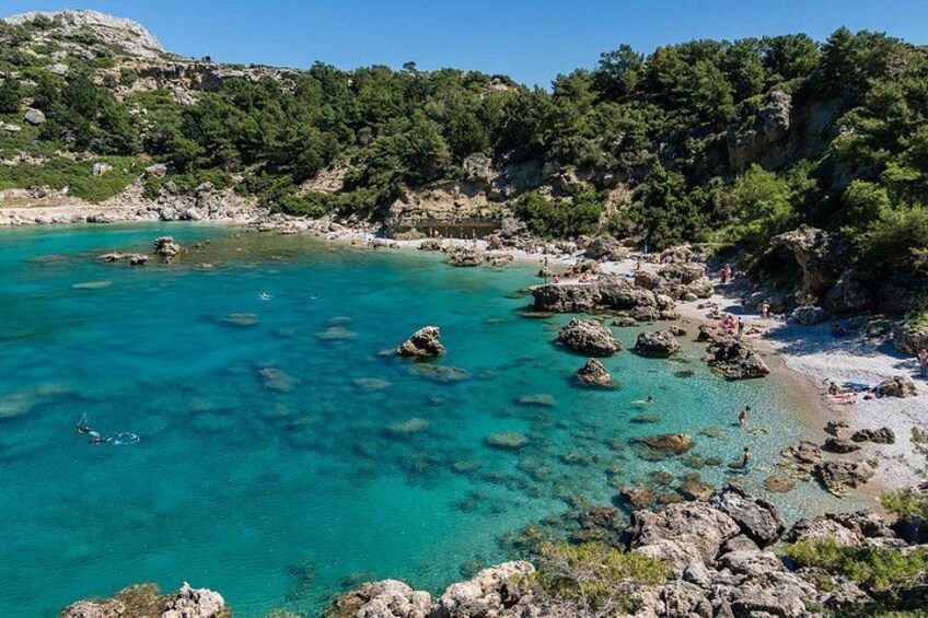 Un paysage côtier caractérisé par une eau turquoise cristalline, des affleurements rocheux et une végétation luxuriante. 5