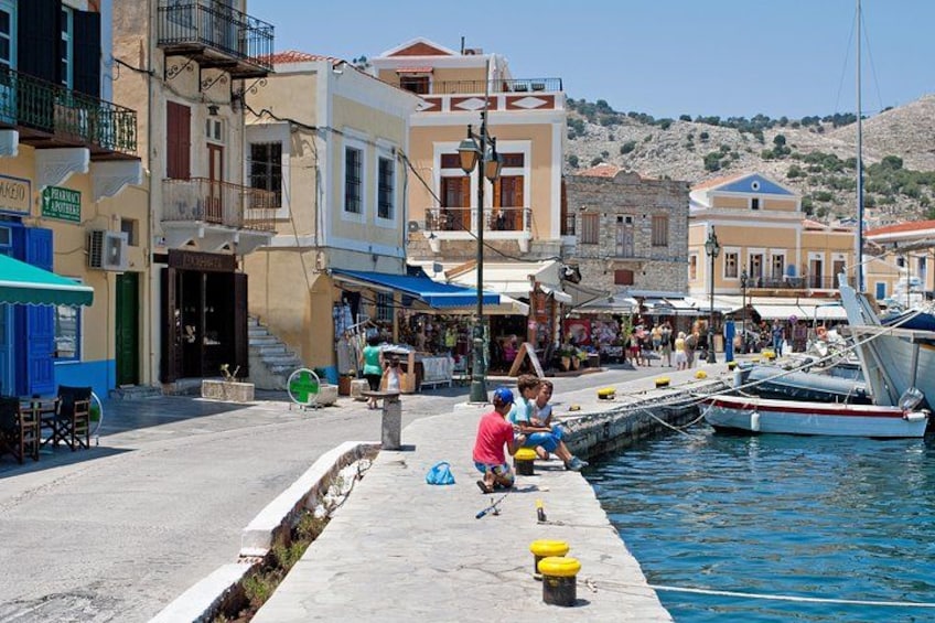 A coastal town with a marina, people sitting by the water, and buildings with balconies. 5