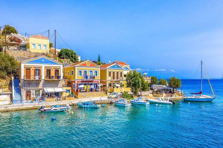 A coastal town with colorful buildings, a marina with boats, and a clear blue sea. 2