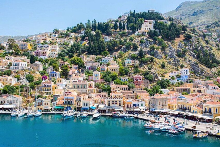 A coastal town with colorful buildings, a marina with boats, and a hillside with structures. 5