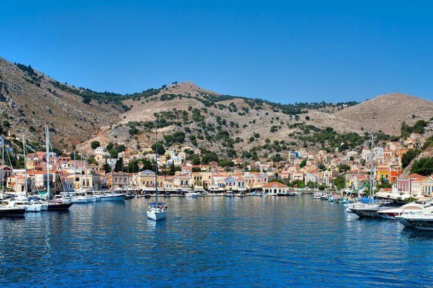 A coastal town with boats docked in a harbor, surrounded by hills and buildings. 5
